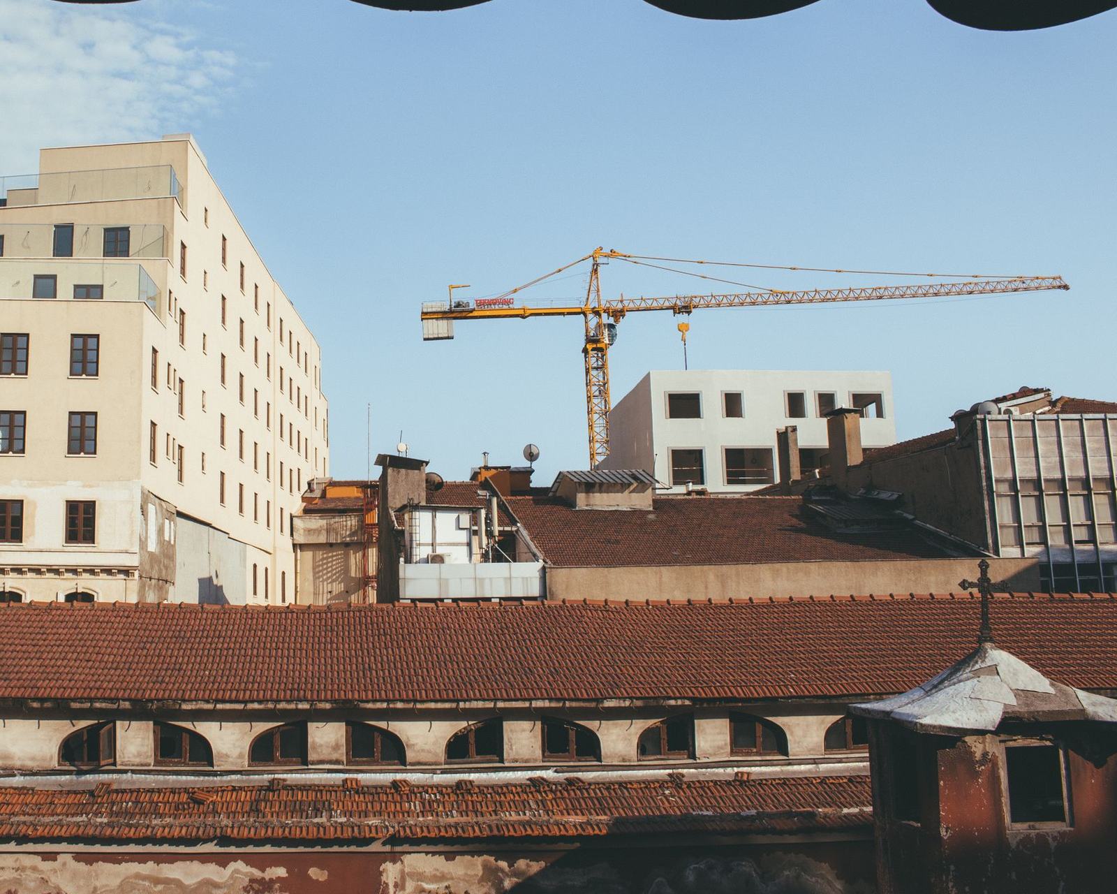 A tower crane over a city block under construction, with approval and budget cards from Odoo floating above