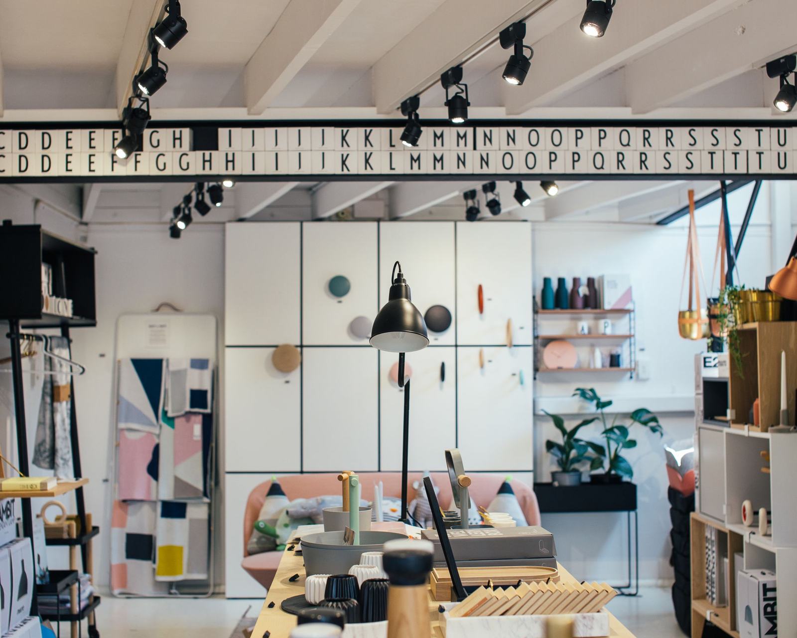 A bright concept store interior with display shelves and track lighting, with web order, stock and e-Arşiv cards from Odoo floating above